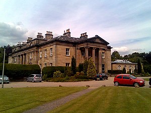 A sandstone two storey Georgian manor home with classical architectural features in a parkland setting